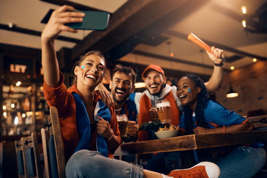 Fan-supporting friends in pub having fun in a pub taking a selie with a mobile phone